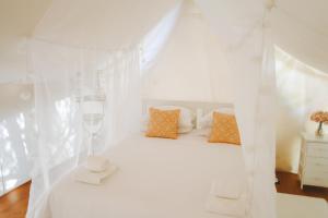 a bedroom with a bed with white sheets and pillows at Kabaceira Glamping in Atalaia