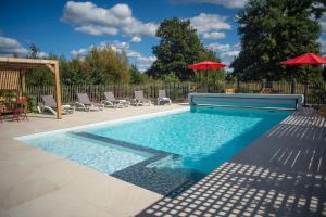 - une piscine avec des chaises et des parasols dans la cour dans l'établissement Le jardin des 4 saisons, au Mans