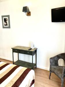 - une chambre avec un bureau, une chaise et une télévision dans l'établissement Hotel Lou Marquès, à Saintes-Maries-de-la-Mer