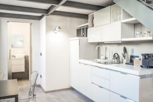 a white kitchen with white cabinets and a table at Brera Apartments in San Marco in Milan