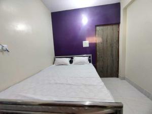 a bedroom with a large bed with a purple wall at OYO The Pine & Dine in Sonpur