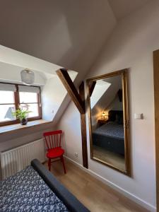 a bedroom with a mirror and a red chair at Apartament Miasteczko in Kazimierz Dolny