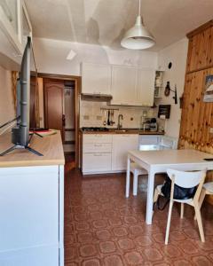 a kitchen with white cabinets and a table and chairs at Scoiattolo Apartment in San Martino di Castrozza