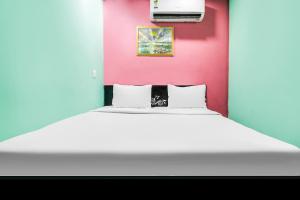 1 dormitorio con cama blanca y pared rosa en Flagship Hotel Rose, en Ballabgarh