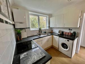 a kitchen with white cabinets and a washer and dryer at Central Cambridge Fig Tree house in Cambridge