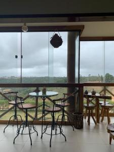 a room with tables and chairs and a large window at APARTAMENTO BANANEIRAS - SONHOS DA SERRA BLOCO E in Bananeiras