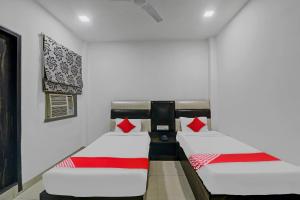 2 camas en una habitación con paredes blancas y almohadas rojas en Capital O Affection Inn, en Chinhat