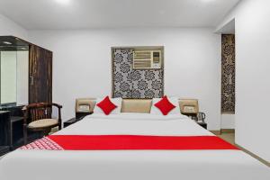 1 dormitorio con 1 cama blanca grande con almohadas rojas en Capital O Affection Inn, en Chinhat