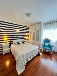 um quarto com uma cama e uma cadeira azul em Cocas House - Alcobaça em Alcobaça