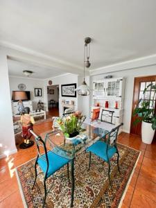 uma sala de jantar com uma mesa de vidro e cadeiras azuis em Cocas House - Alcobaça em Alcobaça