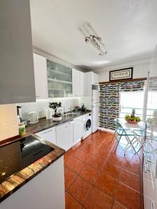 a kitchen with white cabinets and a tile floor at Cocas House - Alcobaça in Alcobaça