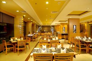 ein Restaurant mit Tischen und Stühlen in einem Raum in der Unterkunft The Quilon Beach Hotel and Convention Center in Kollam