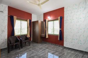 um quarto com duas cadeiras e paredes e janelas vermelhas em OYO Flagship 76044 Layeeree Resort em Bālianta
