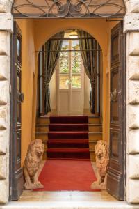 twee standbeelden van katten in een hal met trappen bij Palazzo Mosela Alla Porta in Montepulciano
