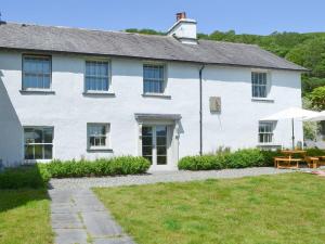 a white house with a table and an umbrella at Souterstead in Torver