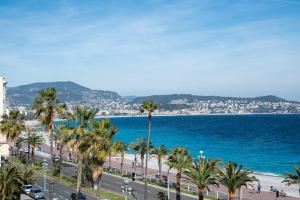 Blick auf einen Strand mit Palmen und das Meer in der Unterkunft Happyfew Palazzo del sol in Nizza