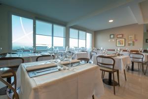 a restaurant with white tables and chairs and windows at ILLIA 121 APART HOTEL in Neuquén