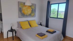 a bedroom with a bed with yellow pillows and a window at "Casa Oliveiras" studio avec terrasse et piscine in Loulé +51 photos