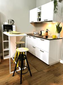 una cocina blanca con encimera y 2 taburetes en Room114 - Studio apartment near the center, en Florencia