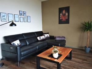 a living room with a black leather couch and a table at Ferienwohnung Wilde7 in Seebach