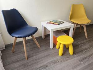 twee stoelen en een tafel met een gele kruk bij Ferienwohnung Wilde7 in Seebach