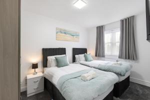 two beds sitting next to each other in a bedroom at Roomy 3 bedroom house, 2 baths in Edgware