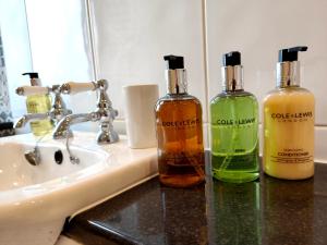 three bottles of soap sitting on a bathroom sink at Grove House in Egremont