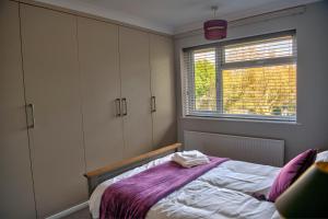 een slaapkamer met een bed met paarse lakens en een raam bij Oakland in Kettering