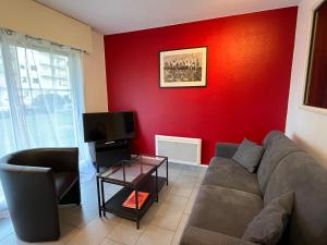 ein Wohnzimmer mit einem Sofa und einer roten Wand in der Unterkunft Dube YourHostHelper in Caen