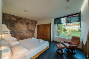 a bedroom with a bed and a chair and a window at Design & Wine Hotel in Caminha