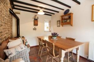 een eetkamer met een houten tafel en stoelen bij Honey Barrel Cottage in Stiffkey