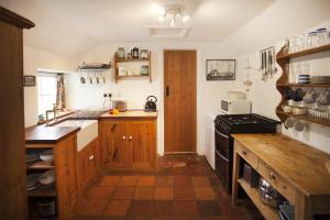 een keuken met houten kasten en een fornuis bij Honey Barrel Cottage in Stiffkey +10 foto's