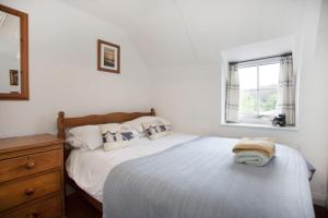 een witte slaapkamer met een bed en een raam bij Honey Barrel Cottage in Stiffkey