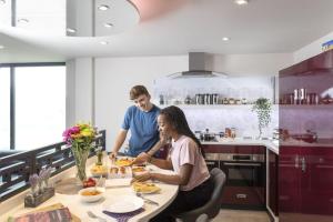 For Students Only Ensuite Bedrooms with Shared Kitchen at Triumph House in Nottingham في نوتينغهام: رجل وامرأة يجلسون على طاولة في مطبخ
