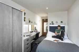 a man sitting on a bed in a bedroom at For Students Only Ensuite Bedrooms with Shared Kitchen at Triumph House in Nottingham in Nottingham