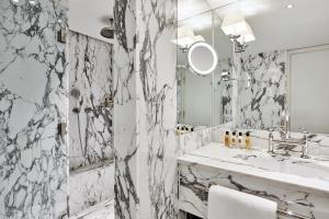 ein weißes Badezimmer mit einem Waschbecken und einem Spiegel in der Unterkunft De L’Europe Amsterdam – The Leading Hotels of the World in Amsterdam
