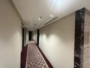 Emaar Elite Al Madina Hotel في المدينة المنورة: ممر به جدار أبيض وأرضية من البلاط