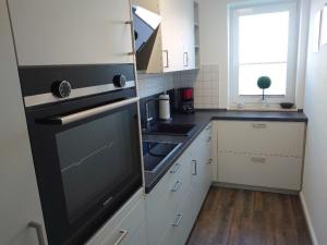 a kitchen with white cabinets and a black refrigerator at Landruhe in Strukkamp auf Fehmarn