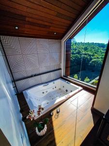 eine große Badewanne in einem Zimmer mit einem großen Fenster in der Unterkunft Refúgio Galli in Encantado
