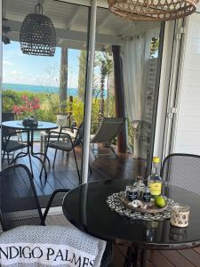 une terrasse couverte avec une table et des chaises. dans l'établissement Indigo Palmes, à Sainte-Rose