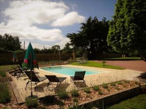 una piscina con sillas y sombrillas en un patio en Les Quintanes, en Suaux