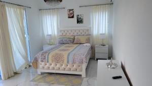 a white bedroom with a bed and two windows at Madome Aparta Hotel in Pedernales