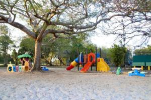 einen Spielplatz in einem Park mit einem Baum in der Unterkunft Apartamento BOUTIQUE con encanto en Juan Dolio-Metro Country Club-CON PISCINA, SEGURIDAD PRIVADA, ENERGIA 24-7, CAMPO DE GOLF Y TENIS in Juan Dolio