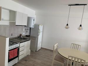 a kitchen with a table and a kitchen with white appliances at Luminoso monoambiente en Rosario in Rosario