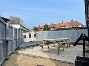 two picnic tables on a patio next to a fence at The Beach Huts in Hornsea