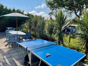 - une table de ping-pong bleue avec un parasol sur la terrasse dans l'établissement Roselands Caravan Park, à Saint Just