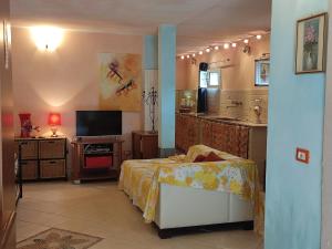 a bedroom with a bed and a tv and a kitchen at La Sorgente Appartamento con piscina privata in Calice Ligure