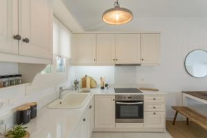 a kitchen with white cabinets and a sink and a stove at Piperi-2 Bedroom home in Naousa