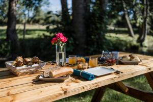 a wooden picnic table with bread and food on it at Le Moulin des Forges in Sainte-Suzanne