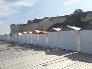 une rangée de cabanes de plage en face d'une falaise dans l'établissement chez Mirka 2 chambres, à Criel-sur-Mer
